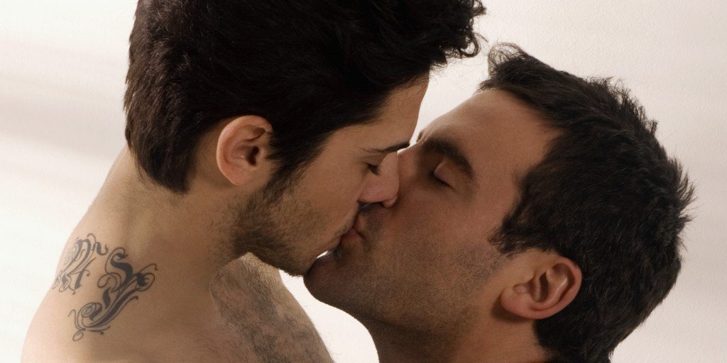 Profile of two shirtless gay men kissing