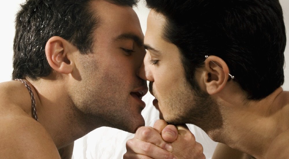 Profile of two shirtless gay men kissing