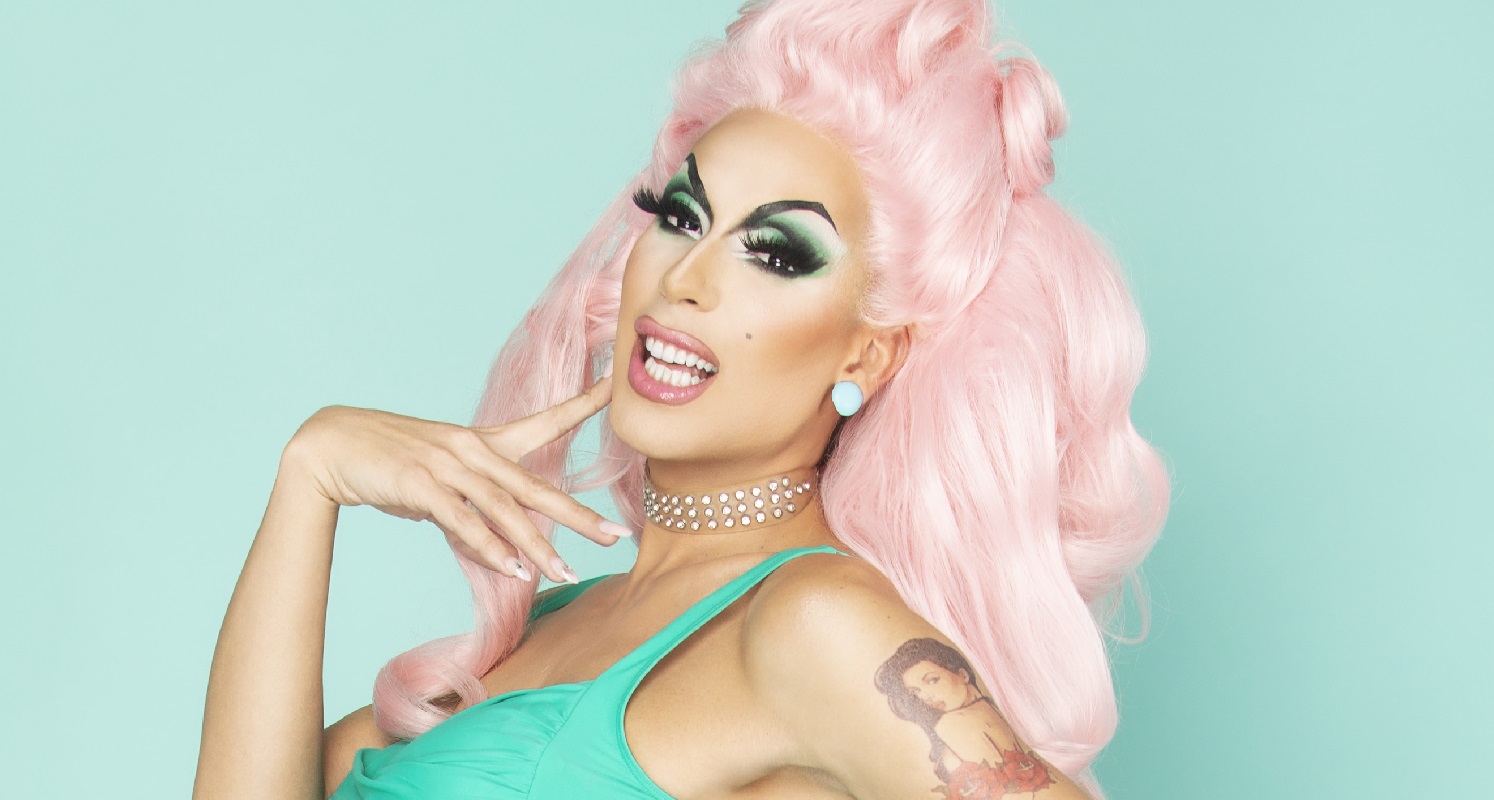 A drag queen in a pink wig and green dress