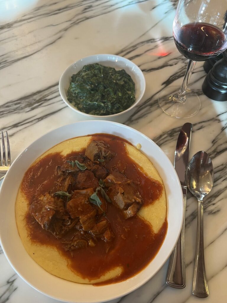 The lamb shoulder, polenta, side order of creamed spinach and a glass of red wine