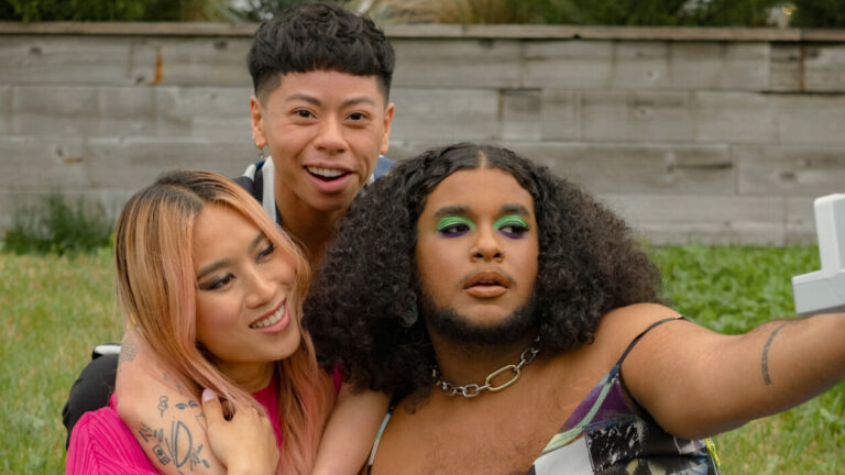 An image of three friends taking selfies in a park