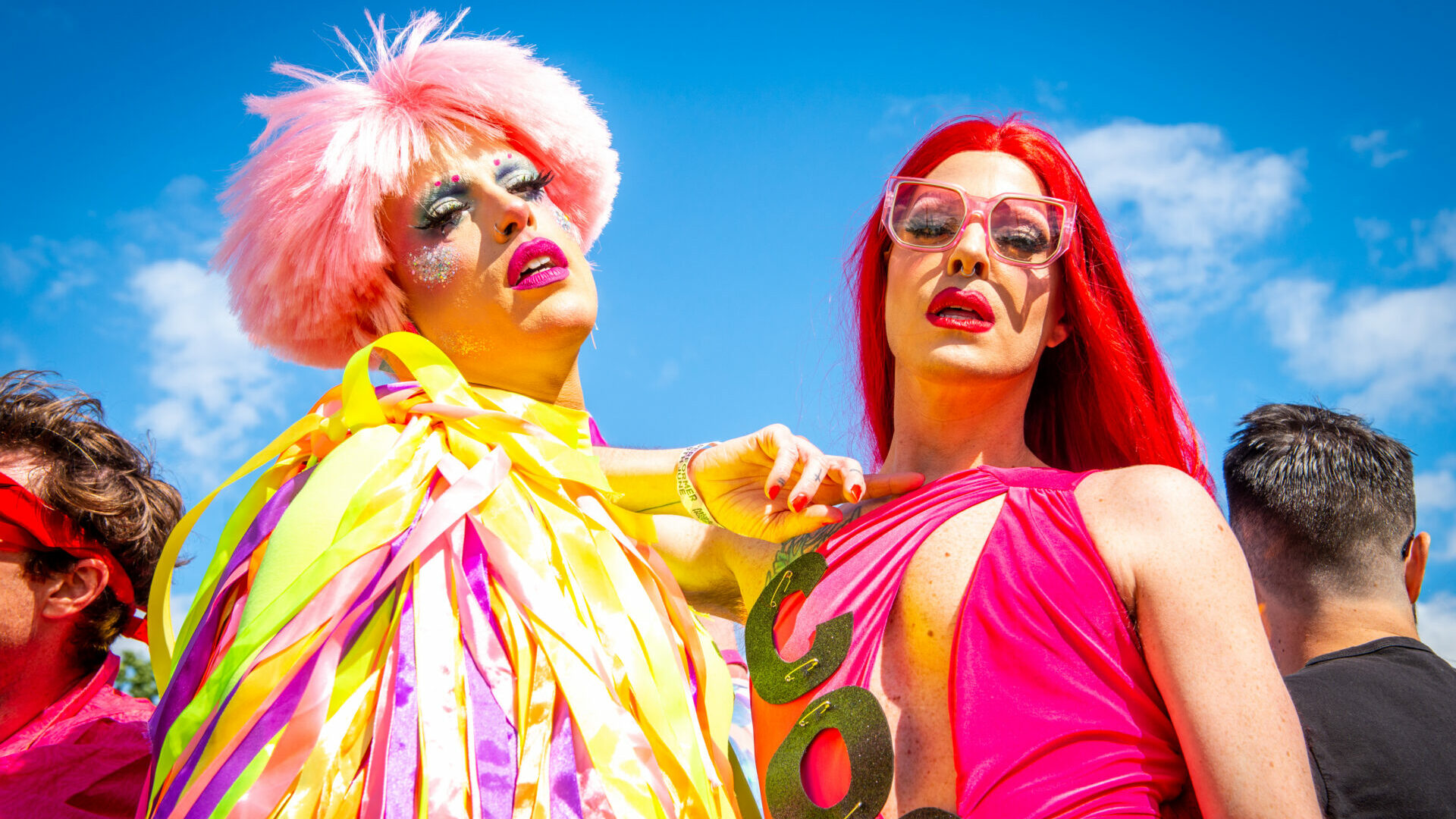 Two people in colourful clothing pose at a festival