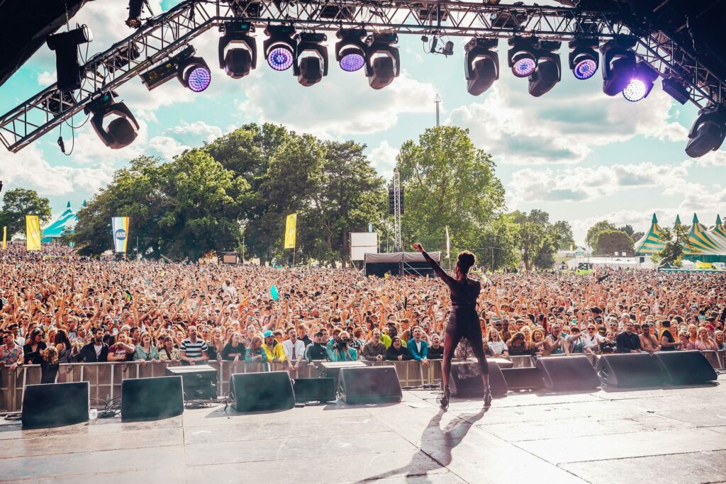 A singer performs on a stage in front of a large crowd