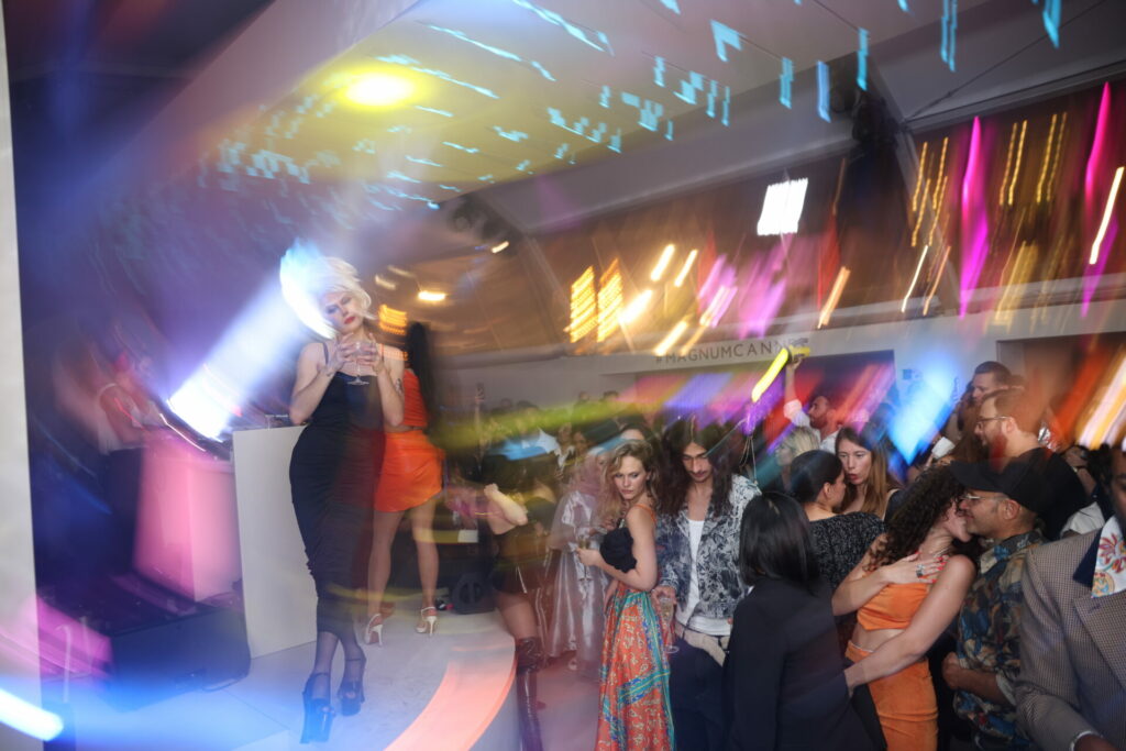 A drag queen stands on a stage in front of an audience