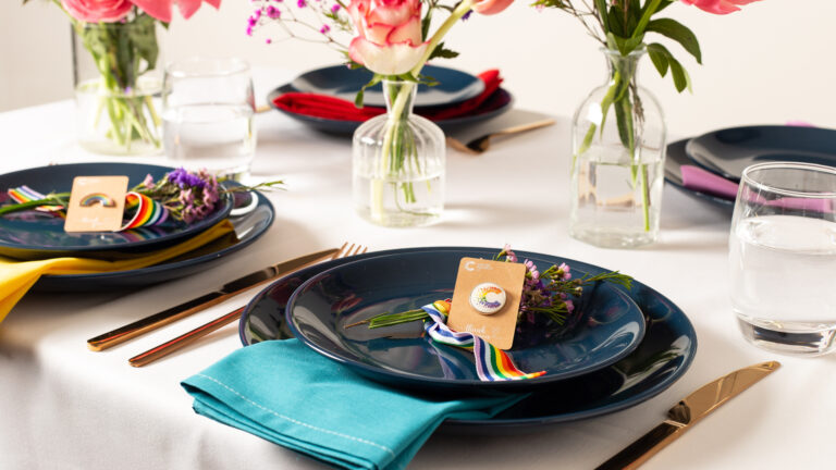 Wedding favours sit on a black plate on a table with a floral arrangement on it