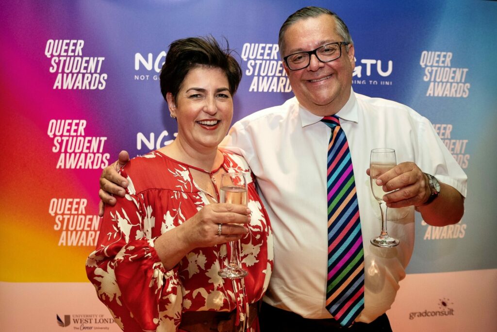 A man and woman at a corporate event holding glasses of alcohol