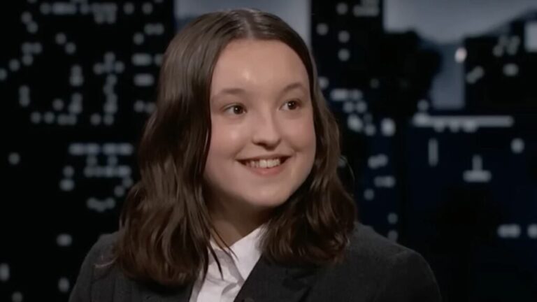 Bella Ramsey dressed in a suit, smiling.