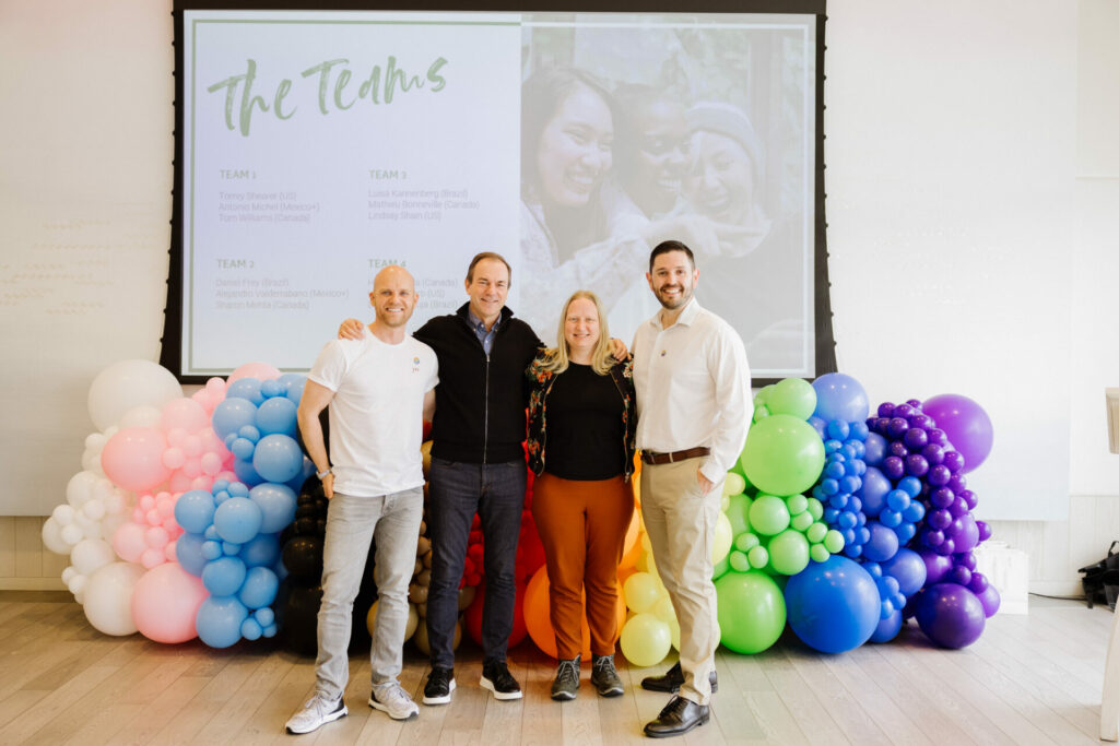 A group of four people stand in front of balloons