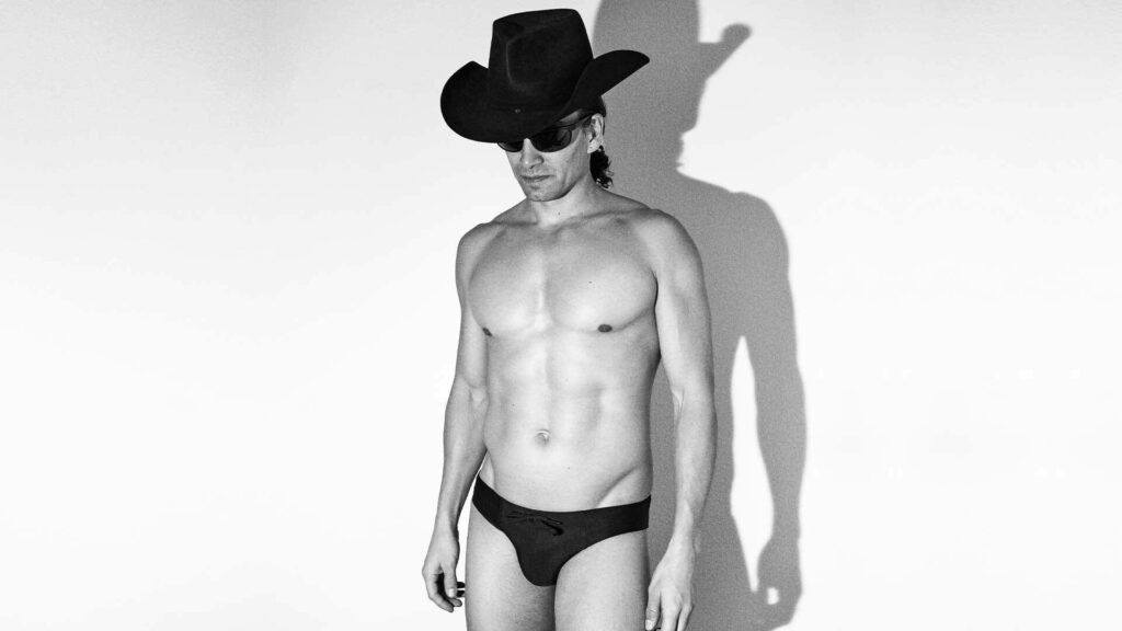 Image of a man wearing a cowboy hat and black swimming briefs