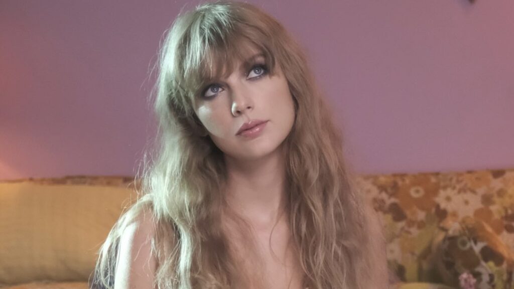 Taylor Swift looks up against a pink backdrop