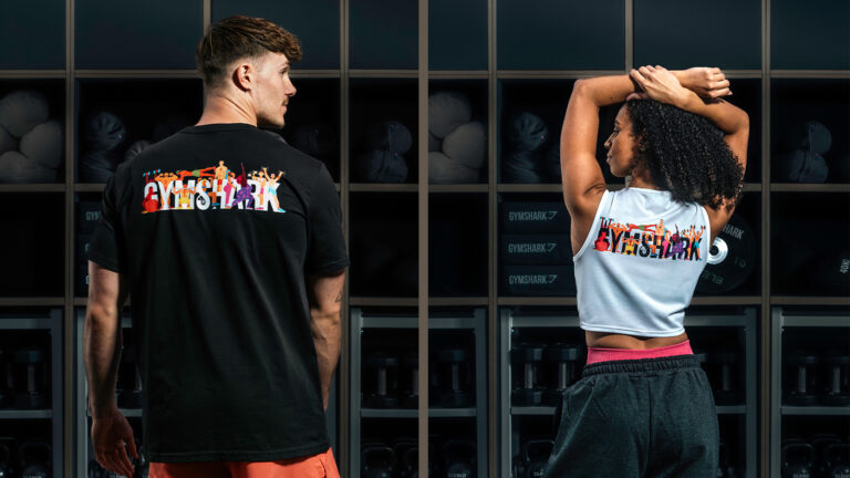 Two models stand with their backs to the camera wearing Pride t-shirts