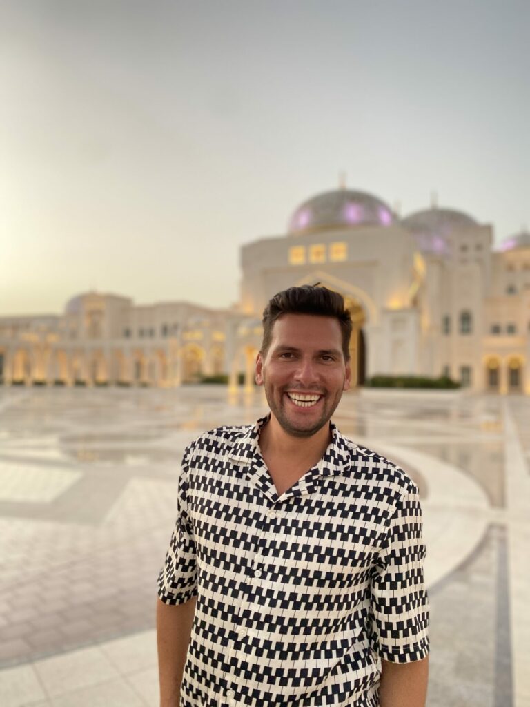 A man standing in front of an ancient landmark wearing a black and white shirt