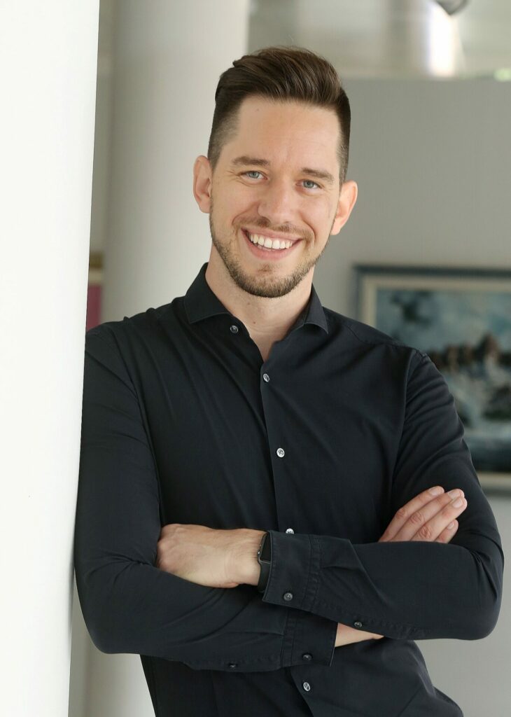 A male with folded arms wearing a black shirt
