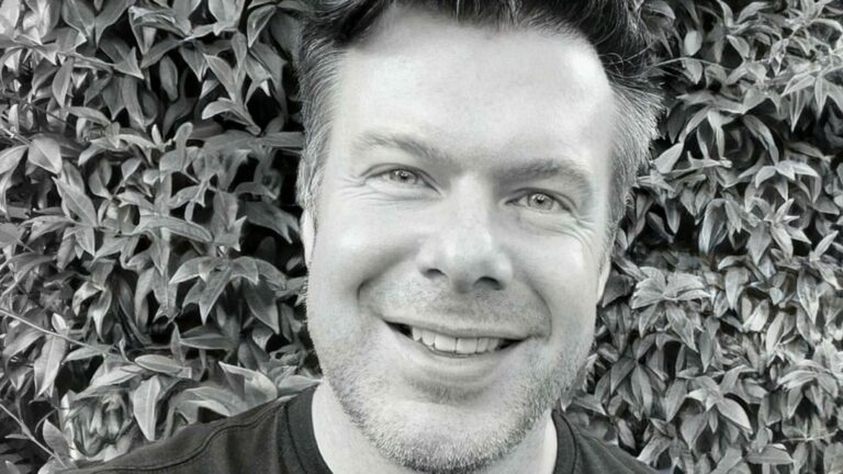 Black and white portrait image of a man smiling into the camera