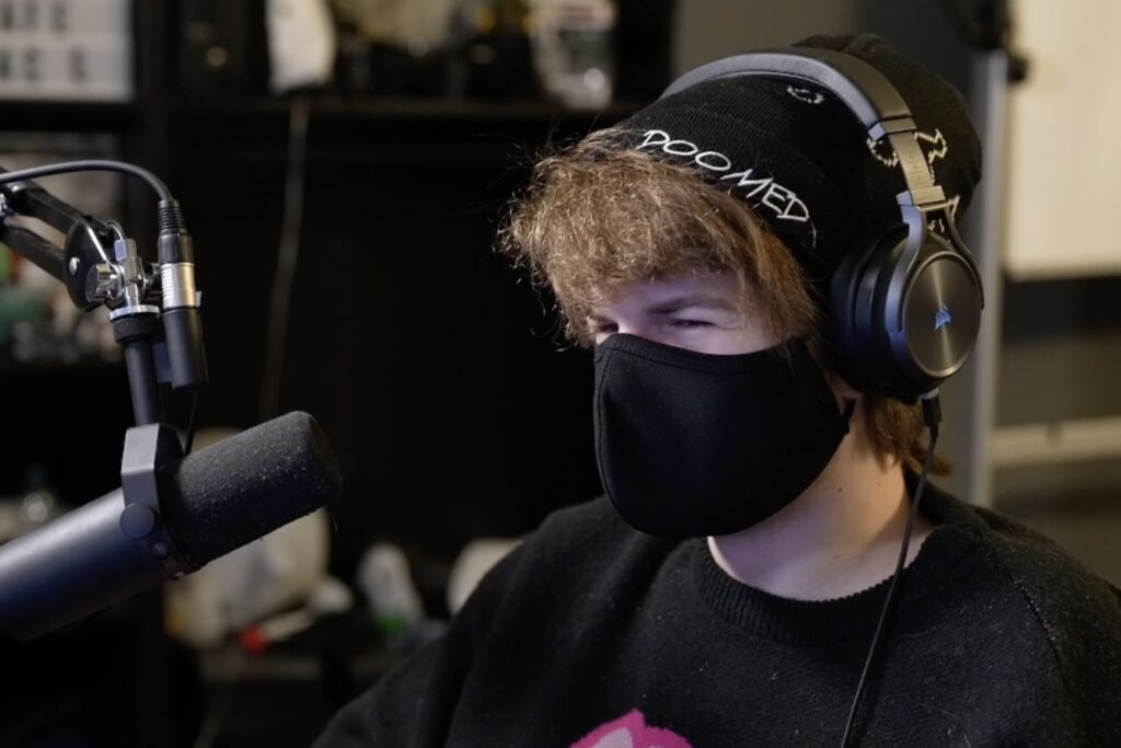 Ranboo streaming, wearing a black face mask, headphones and beanie.