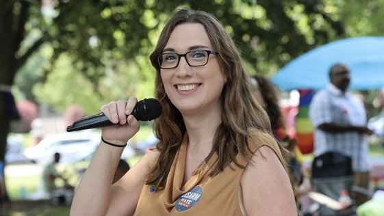 Senator Sarah McBride stood outside smiling with a mic in hand.