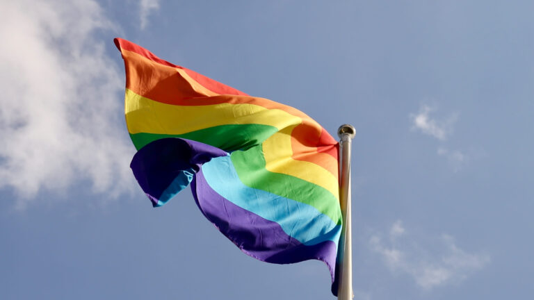 Rainbow flag against blue sky