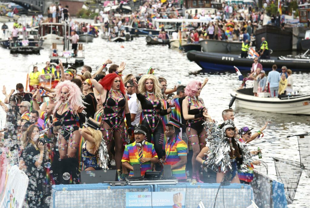 A canal barge floats down an Amsterdam canal with drag queens on board