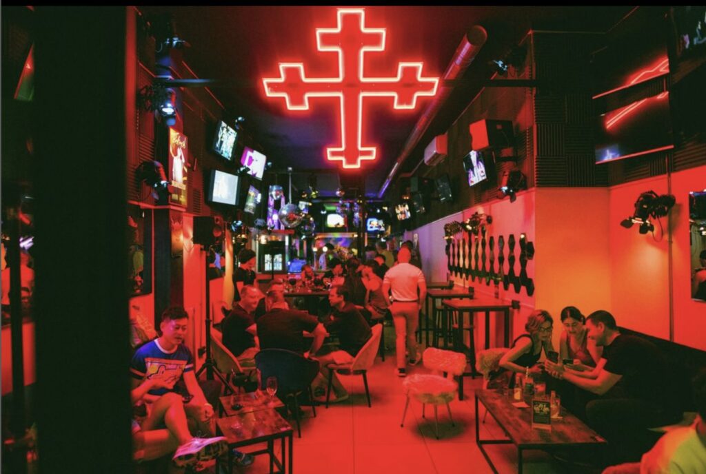 A bar with a red neon crucifix on the ceiling
