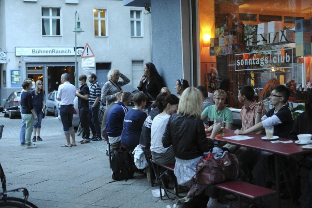 A group of people sit outside a cafe at tables