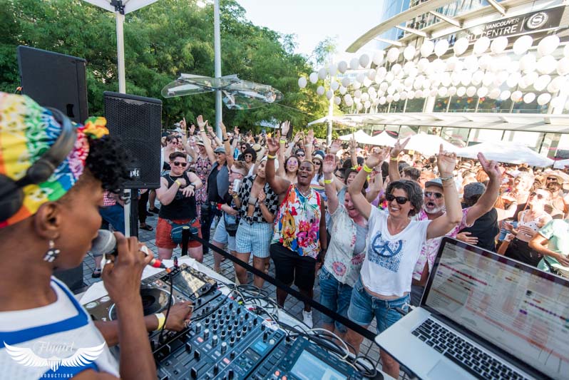 A group of people dance in front of a DJ outdoors