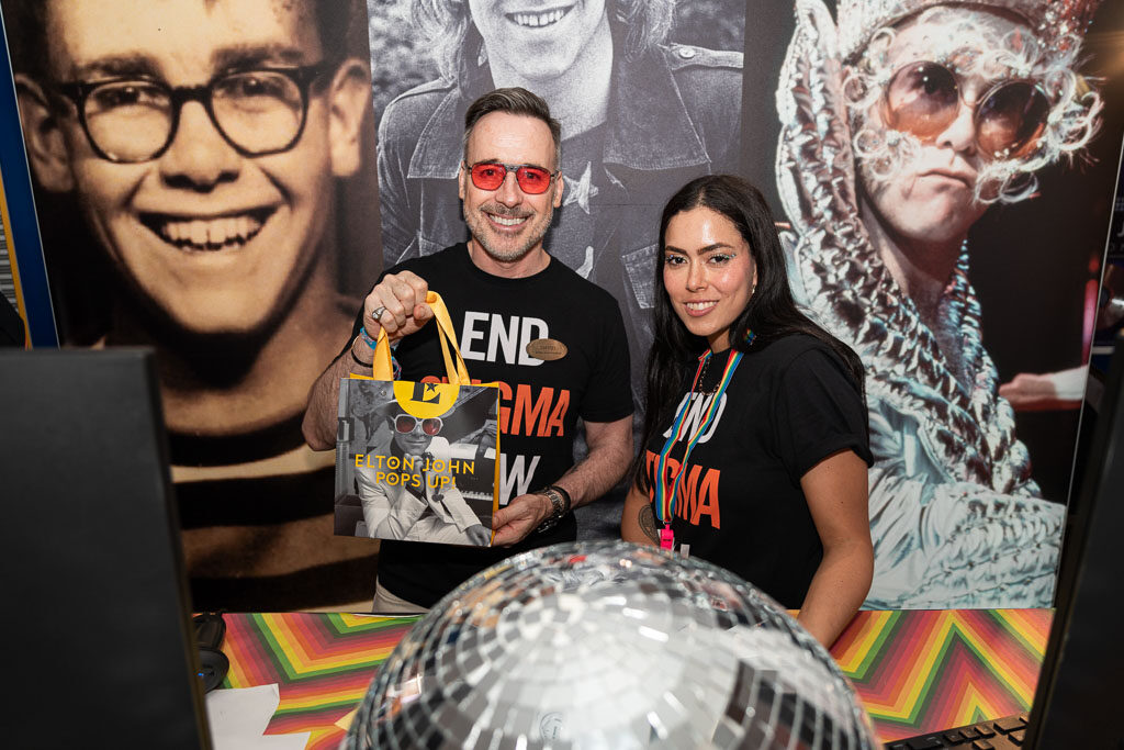 David Furnish and a woman stand in front an Elton John Eyewear store display