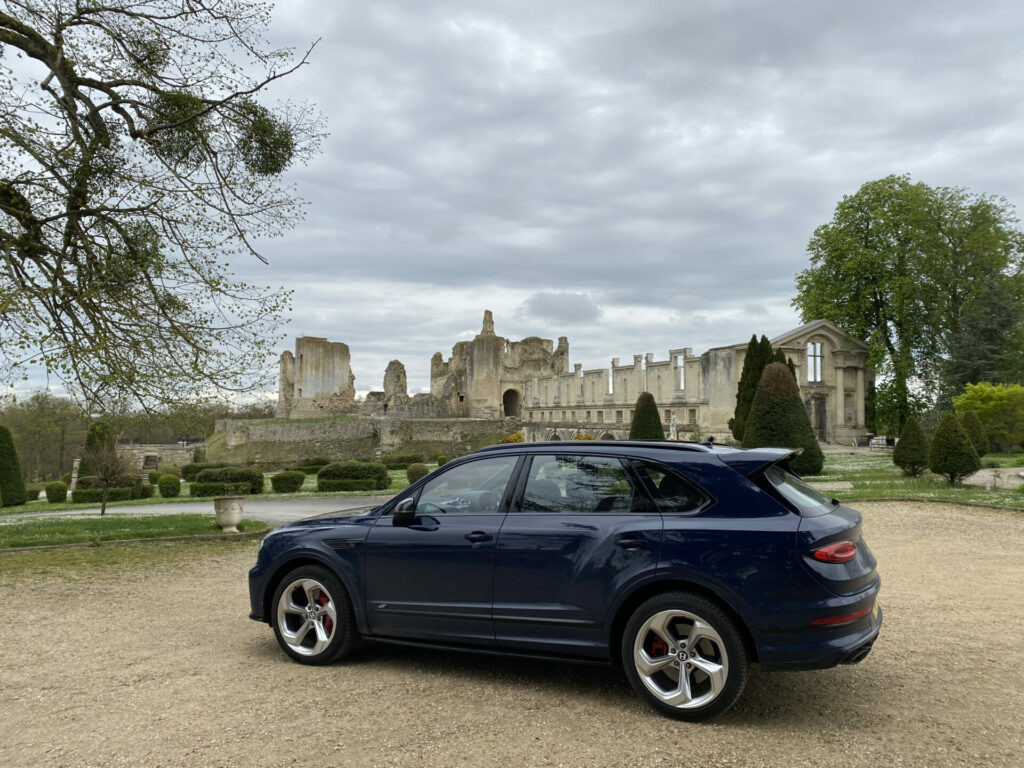 A blue Bentley sits on a driveway