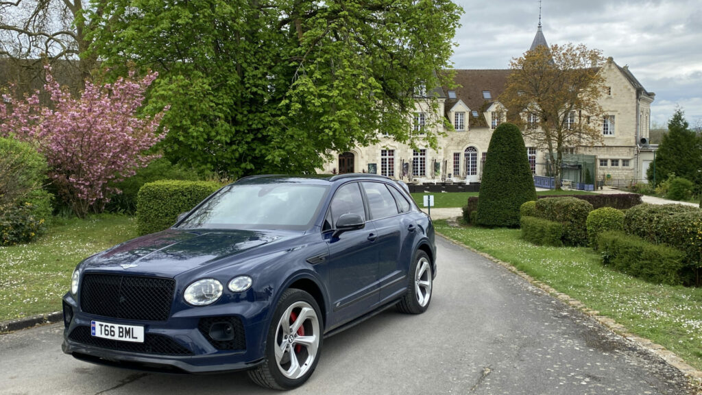 A blue Bentley sits on a driveway