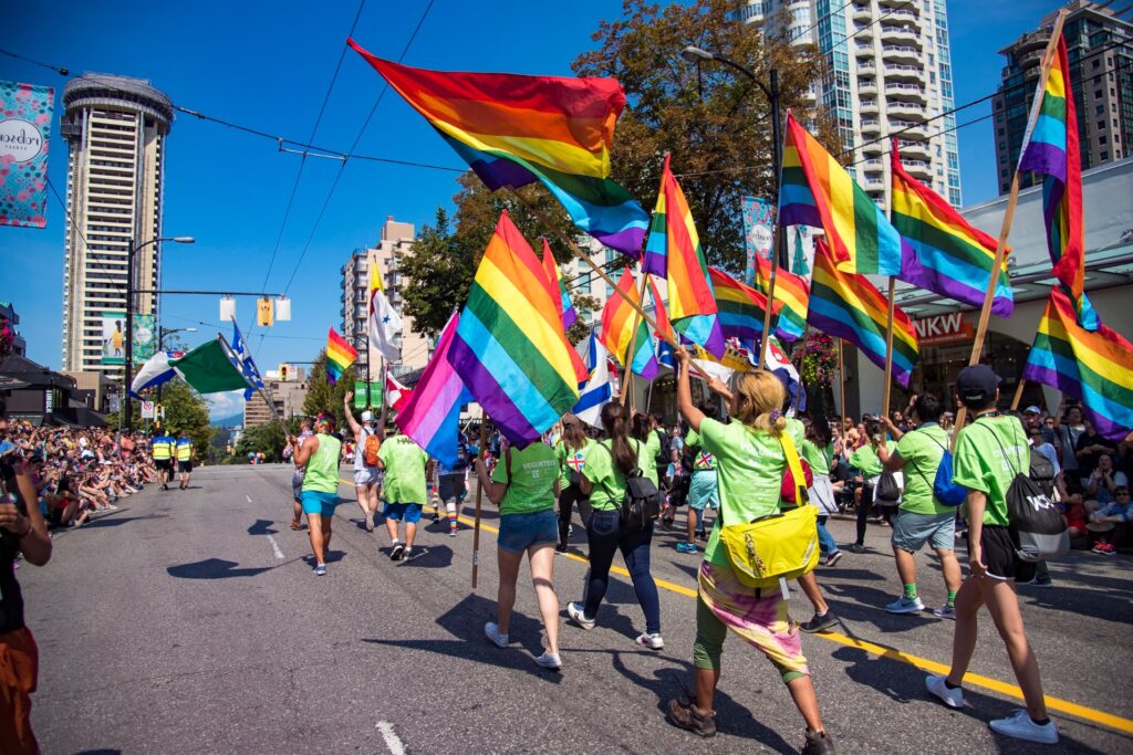 A group of people holding Pride flags march along a street in Vancouver