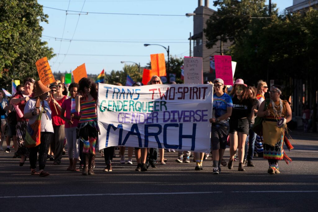 A group of people march in the street holding banners