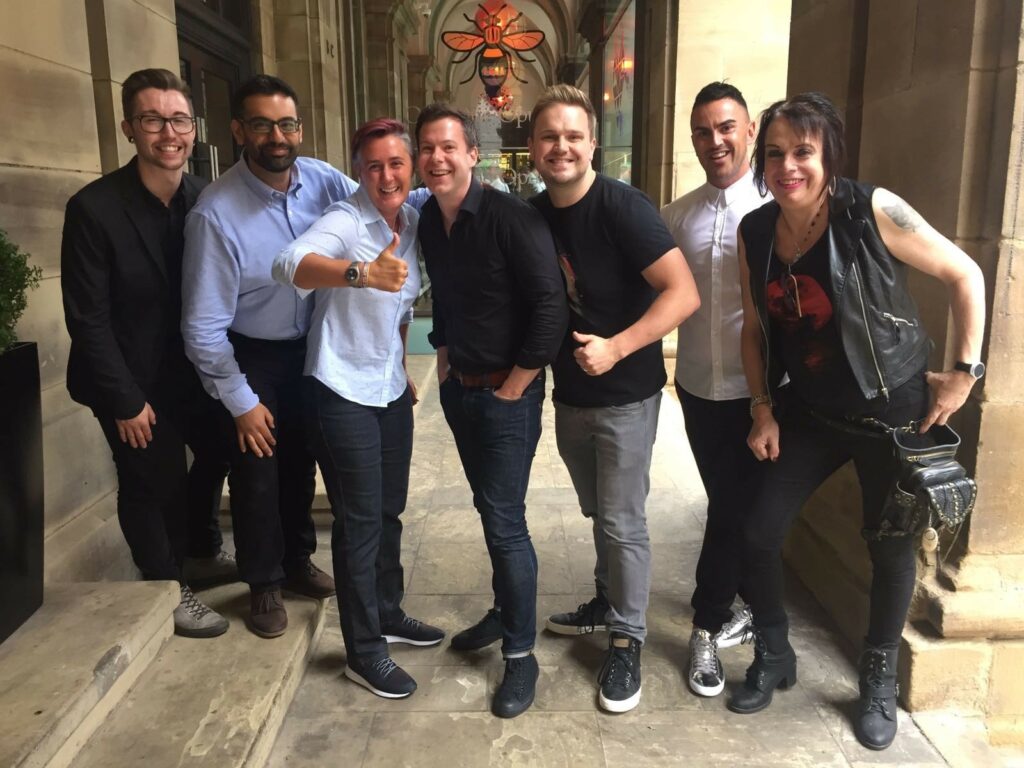 A group of people stand together looking into the camera smiling