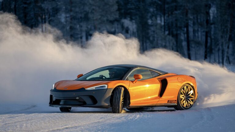 McLaren car doing laps of the circuit - action shot with snow kicked up behind the car.