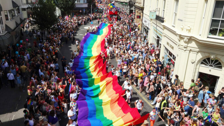 Crowds carry a huge rainbow flag through the streets of Brighton