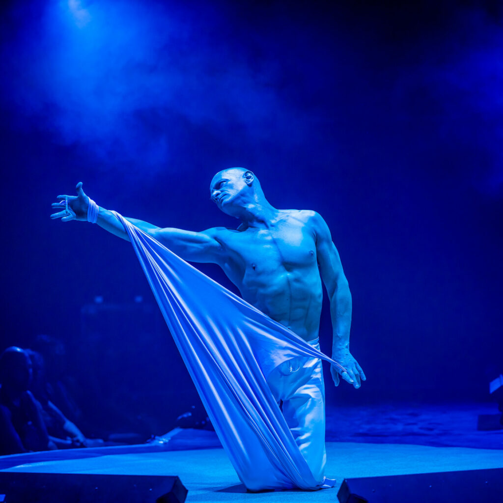 Performer at Sziget festival, a shirtless man stretching fabric.