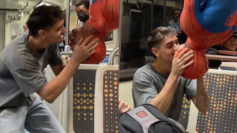A man kissing another man dressed as Spider-Man on the subway