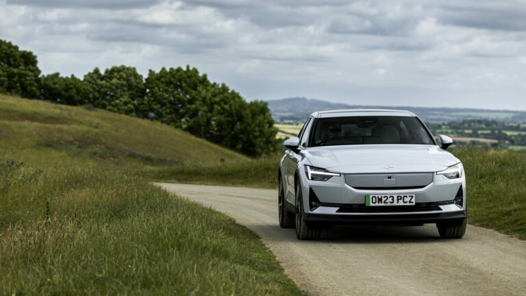 A white car on a road surrounded by green grass