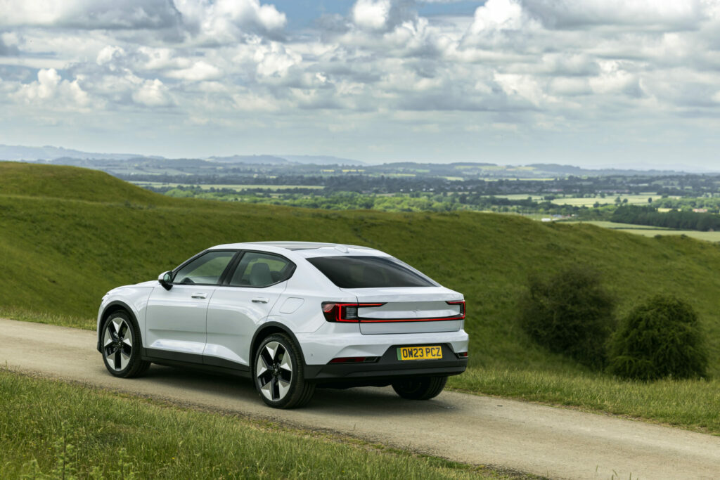 A white car drives through a green landscape