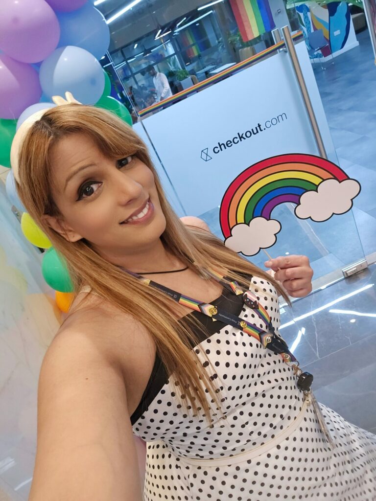 A woman stands in front of a checkout.com sign smiling