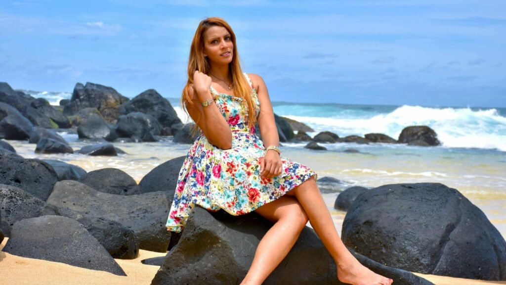 A woman sits on a rock on the beach