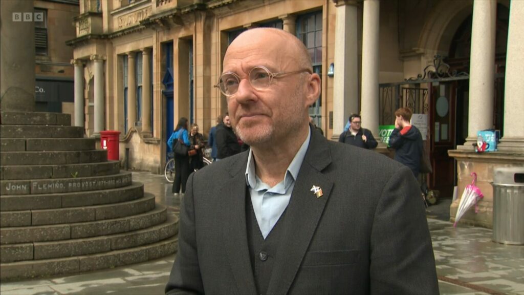 Patrick Harvie stands in front of a building being interview