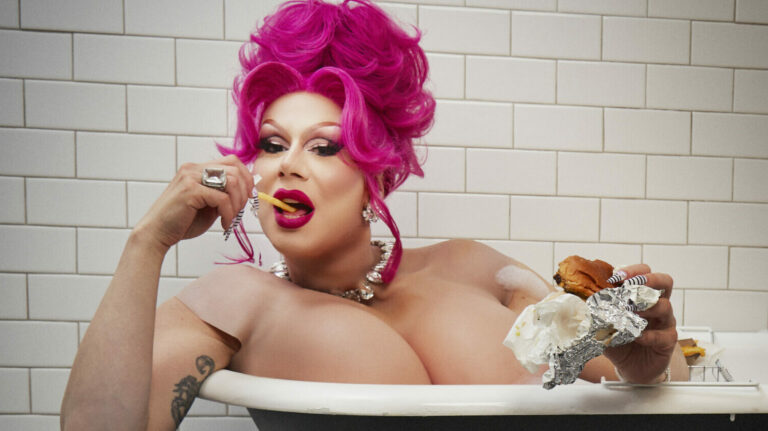 Jimbo in drag eating a burger in the bath, as you do