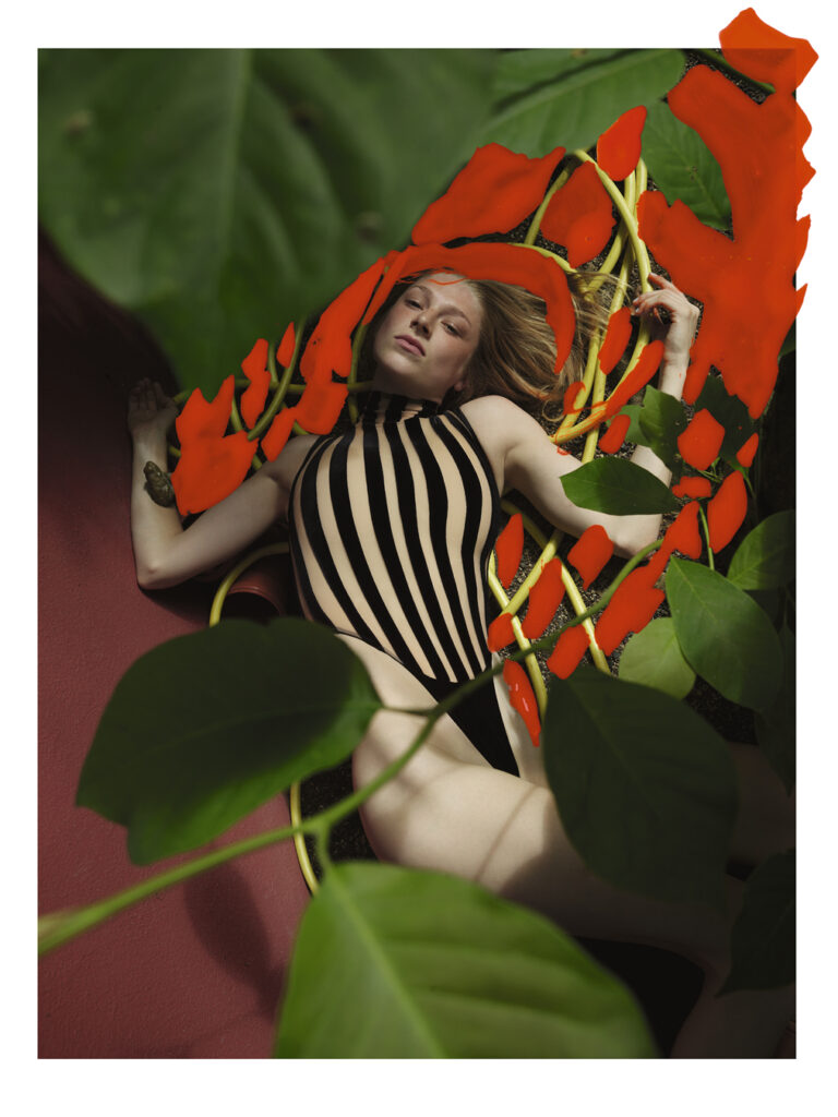 Hunter Schafer laying on red roots and green leaves