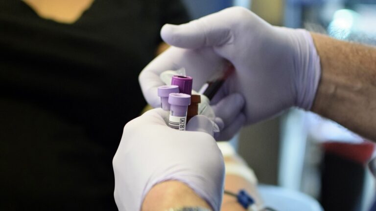 blood test tubes being held my gloved hands