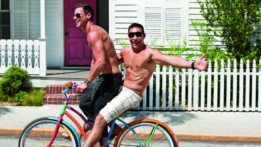 Two shirtless men ride a bicycle in Key West