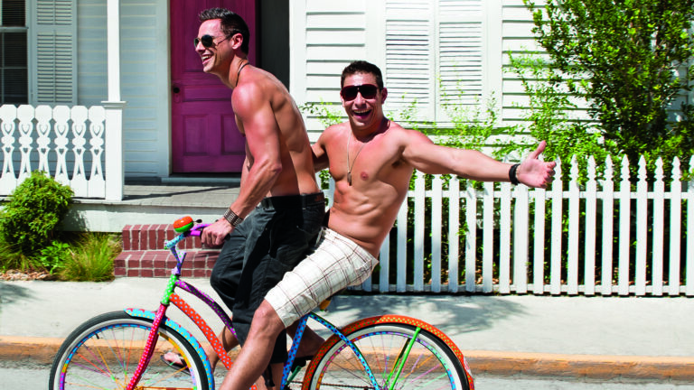 Two shirtless men ride a bicycle in Key West