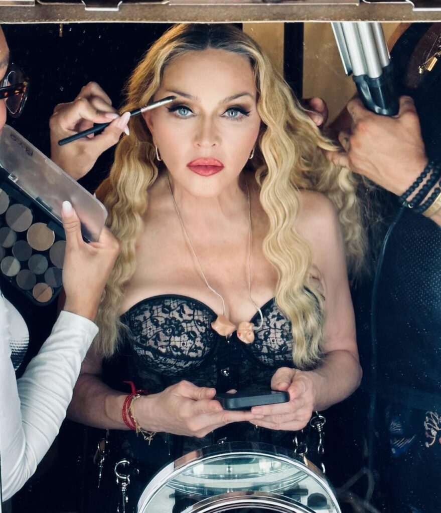 Madonna wearing a corset top while having her makeup done