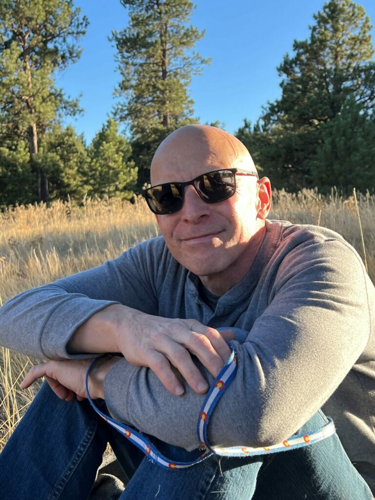 A man sits in a field with sunglasses on