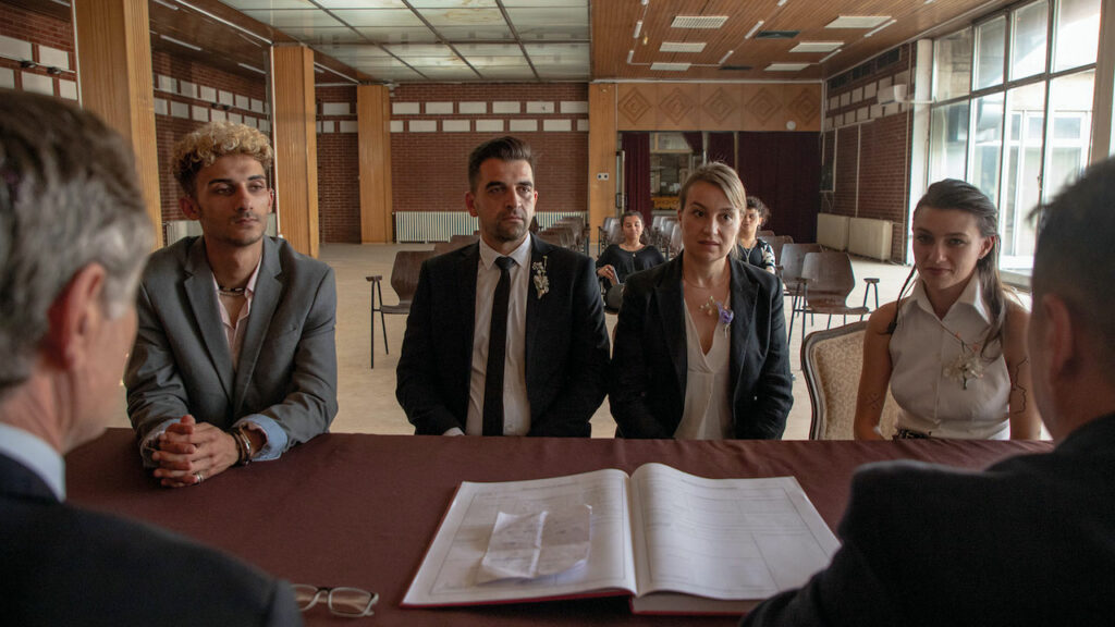 Housekeeping For Beginners film still: found individuals sat arround a table in front of legal documents