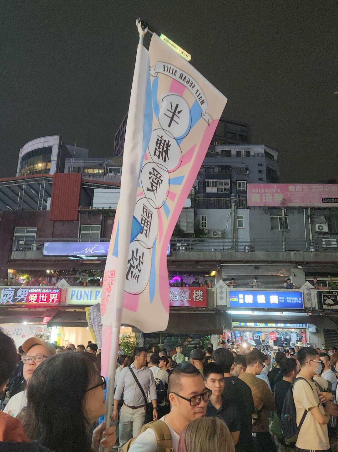 Crowds attend the Taiwan Trans March and wave a flag in Chinese characters