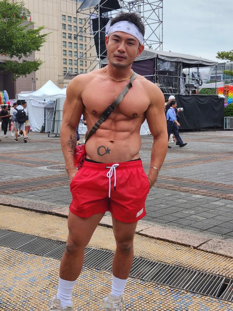 A shirtless man with red shorts and a white headband